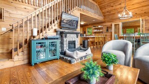 Un intérieur en bois avec une cheminée, un escalier et un coin repas.