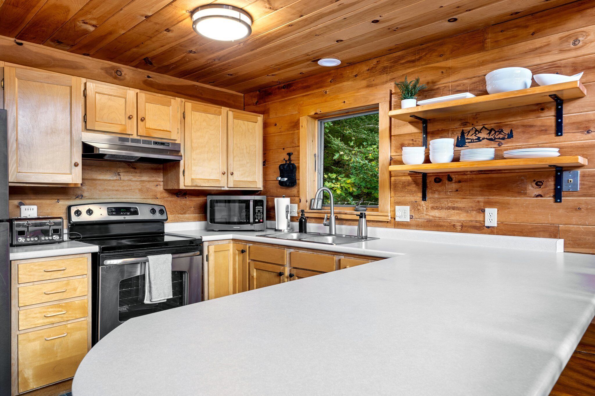 A modern kitchen with wooden cabinetry, stainless steel appliances, and a large island.