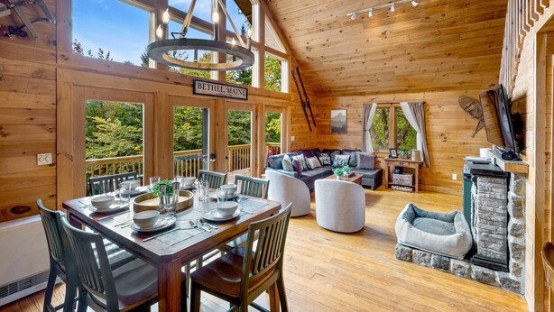 L’intérieur d’un chalet en bois comprend un coin repas, des sièges et une cheminée.