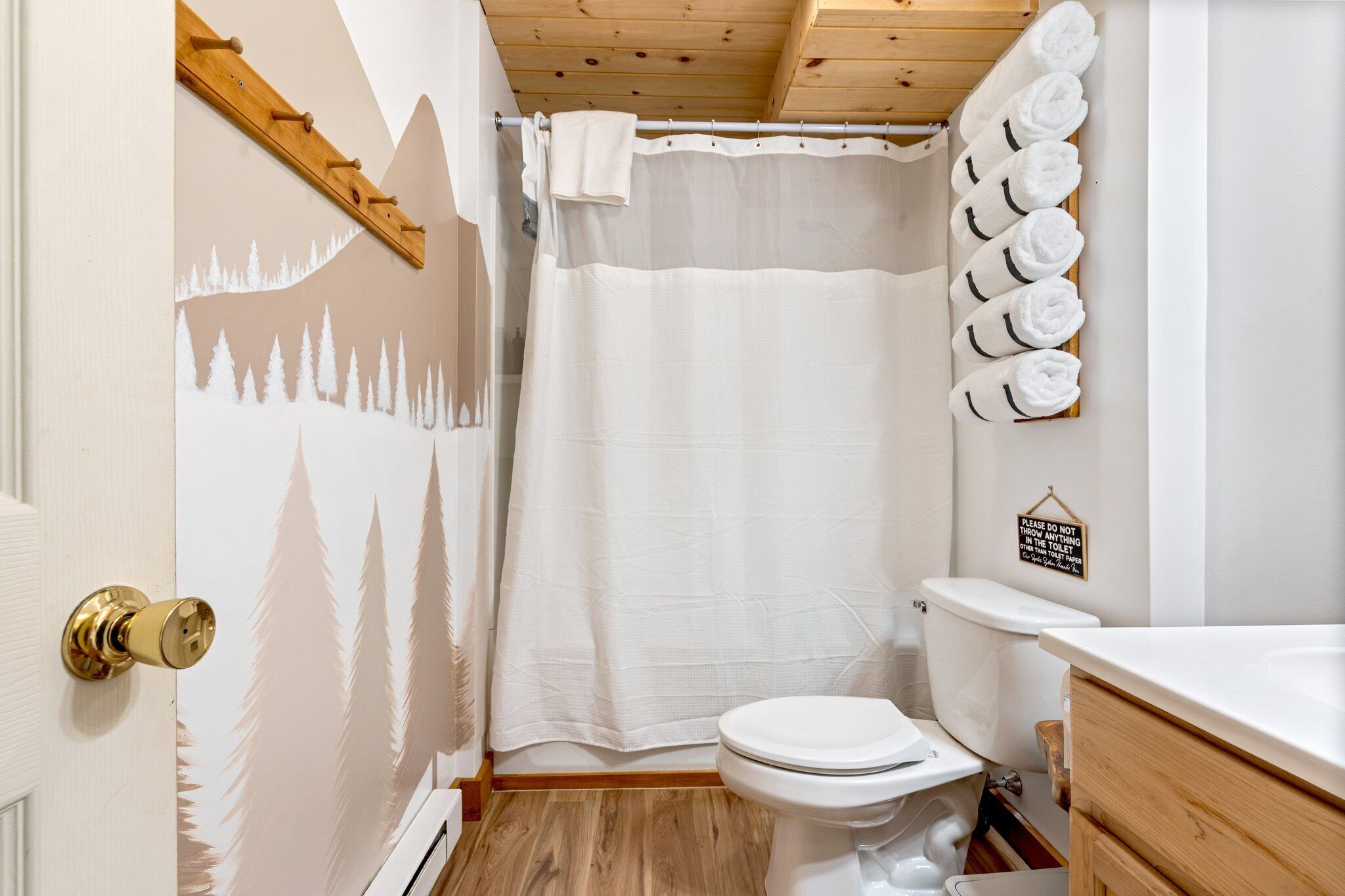 A bathroom with a shower curtain, a toilet, a sink, and a towel rack with towels.