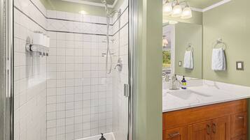 Une salle de bain avec une douche, un lavabo et des meubles en bois.
