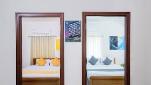 A mirrored view of a bedroom with two beds, each with a wooden frame, white bedding, and multiple pillows.