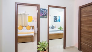 A hotel room with a bed, a potted plant, and a painting on the wall.