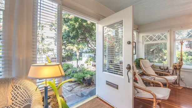 A cozy room with a wooden floor, a sofa, a lamp, and a door leading to a garden. - Vintage Cottage steps from Venice Beach (Los Angeles)