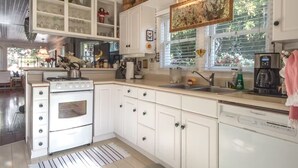 A kitchen with white cabinetry, a stove, a sink, and a window with blinds. - Vintage Cottage steps from Venice Beach (Los Angeles)