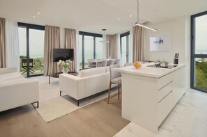 Relax in a spacious living area with a sofa and chairs, a kitchen island, and expansive views of the surrounding landscape.