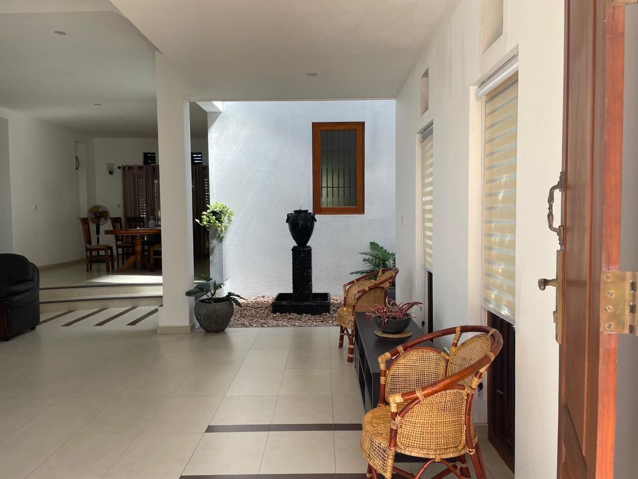 Amplia sala de estar con una mesa y sillas de comedor, un jarro decorativo negro y una planta en maceta.