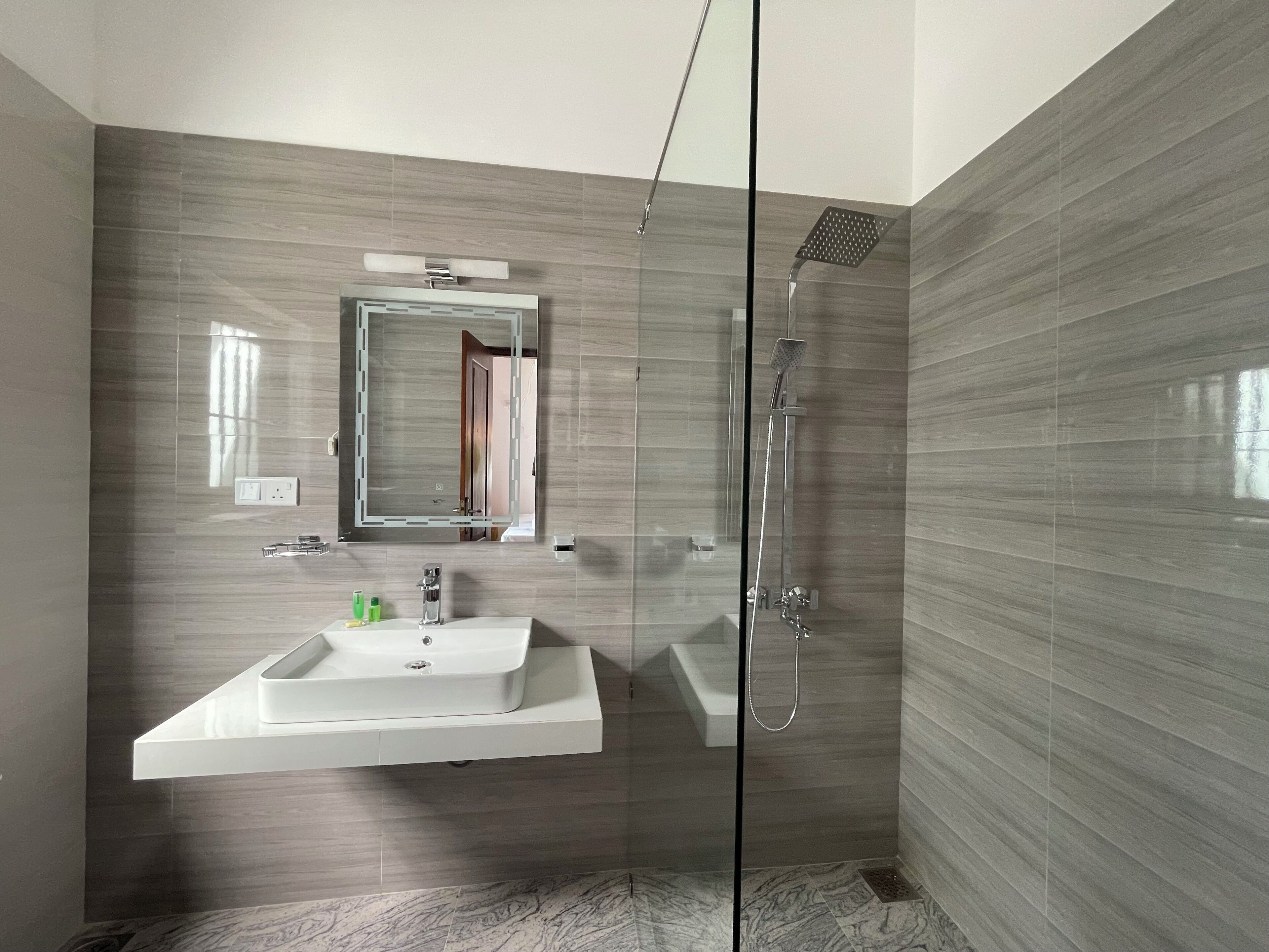 Une salle de bain moderne avec une douche à parois de verre, un lavabo blanc et un miroir au-dessus.