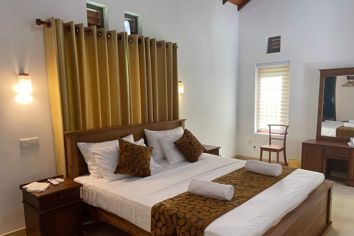 A neatly made bed with a patterned bedspread, a wooden headboard, and a bedside table with a lamp and a phone.