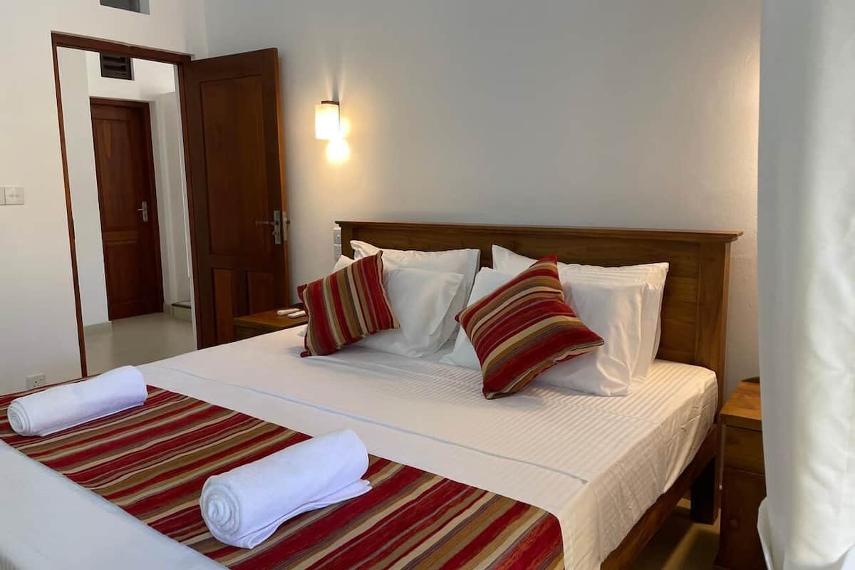 A double bed with striped bedding, two pillows, and a nightstand with a lamp.