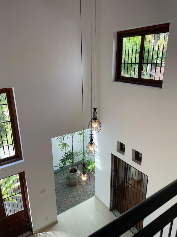 Un interior espacioso con techo alto, múltiples ventanas y lámparas colgantes.