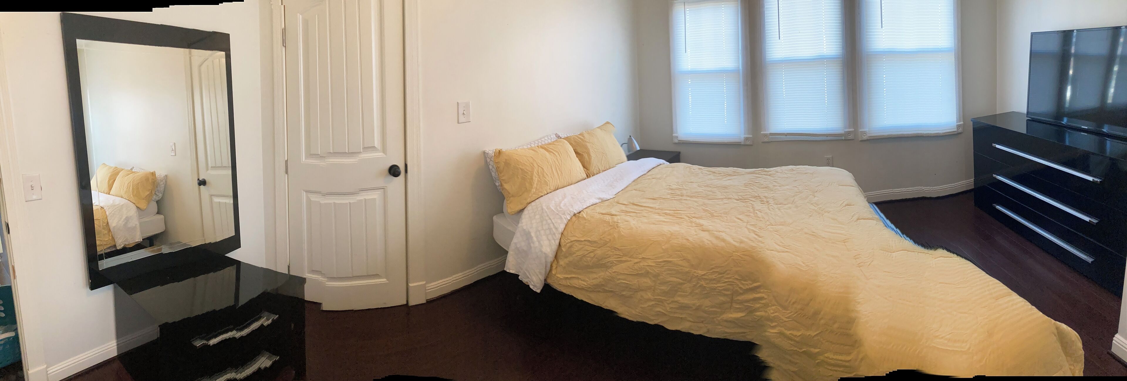 Un dormitorio con cama, cómoda, televisor y puerta.