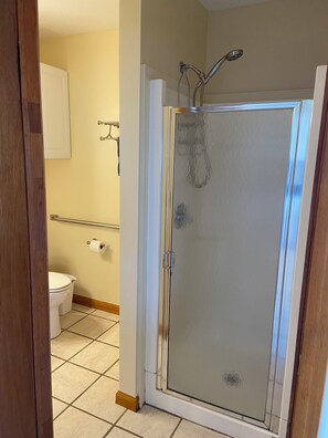 Un baño con cabina de ducha de vidrio, un inodoro y un perchero para toallas.