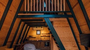 An attic bedroom with a loft bed, a sofa, a chair, and a wooden coffee table. - KARMATTE BUNGALOW  (Kartepe)