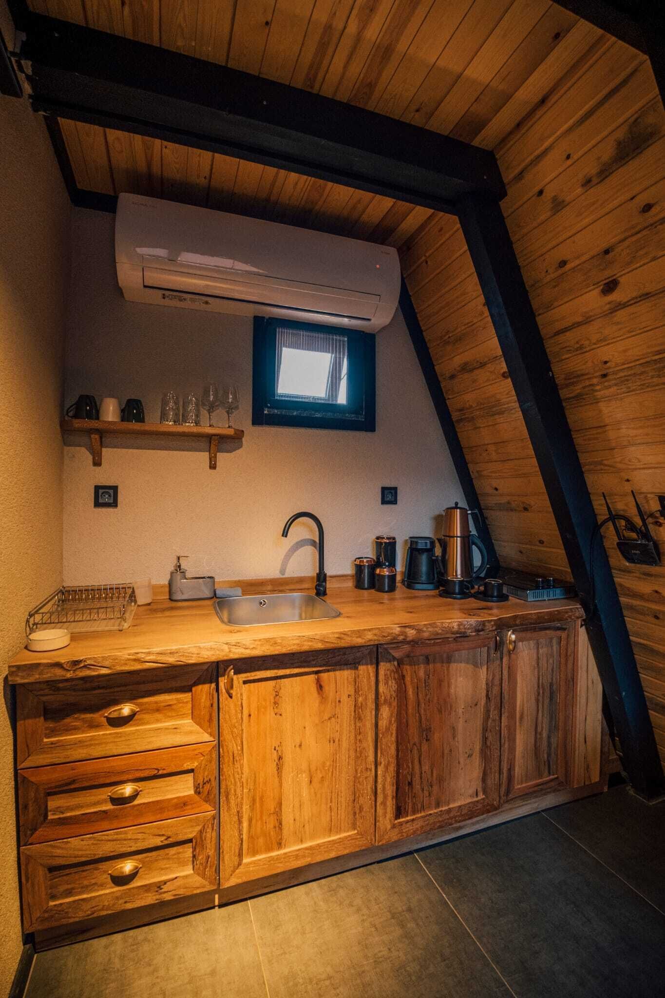 Une cuisine avec des meubles de rangement en bois, un évier et une fenêtre au-dessus du plan de travail.