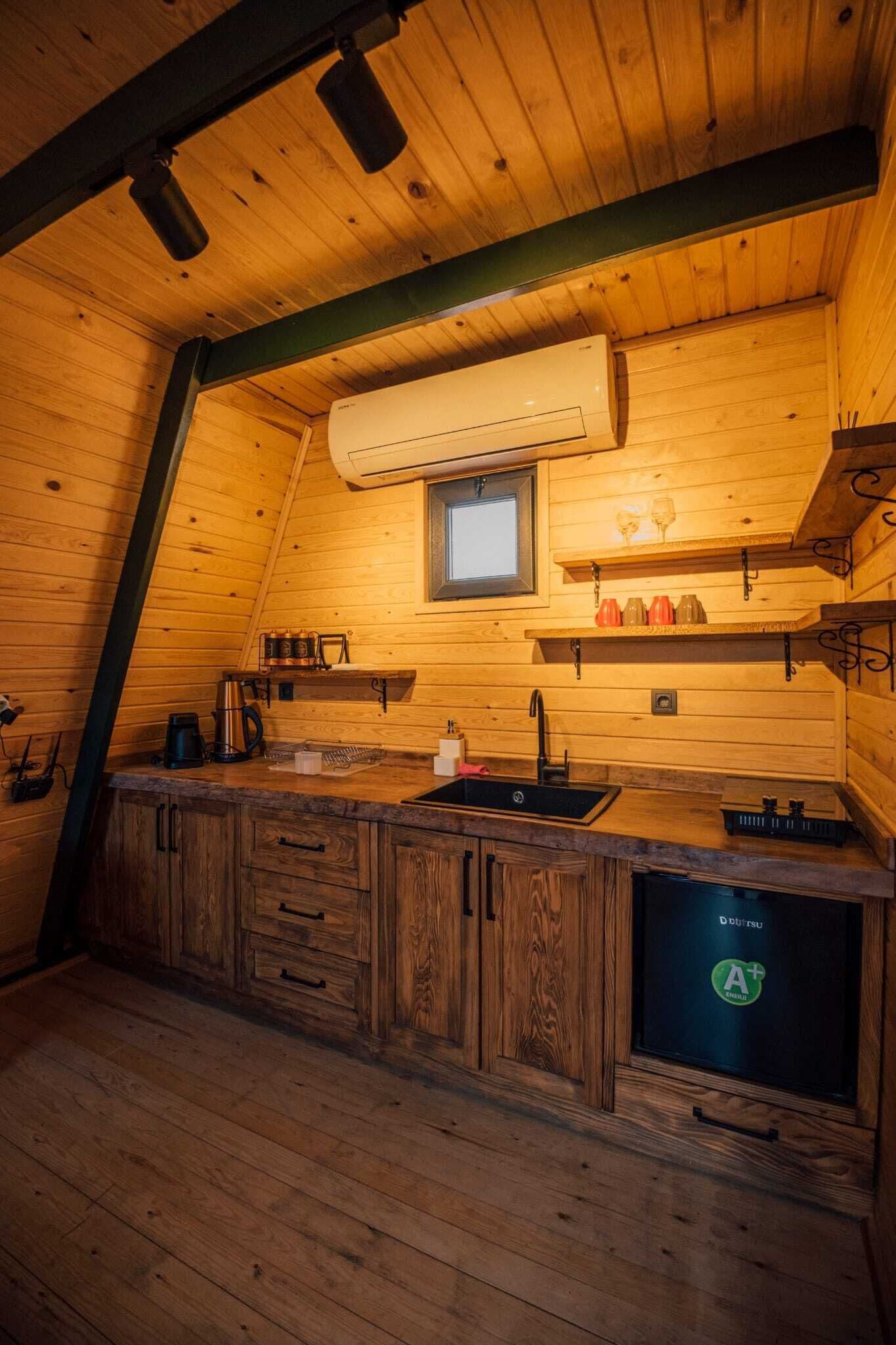 A cozy wooden cabin kitchen with a built-in sink, wooden cabinets, a window, and a built-in oven.