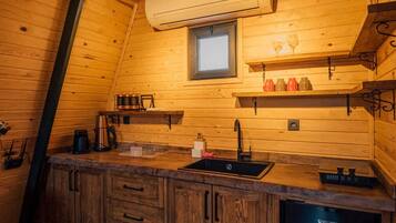 A cozy wooden cabin kitchen with a built-in sink, wooden cabinets, a window, and a built-in oven.