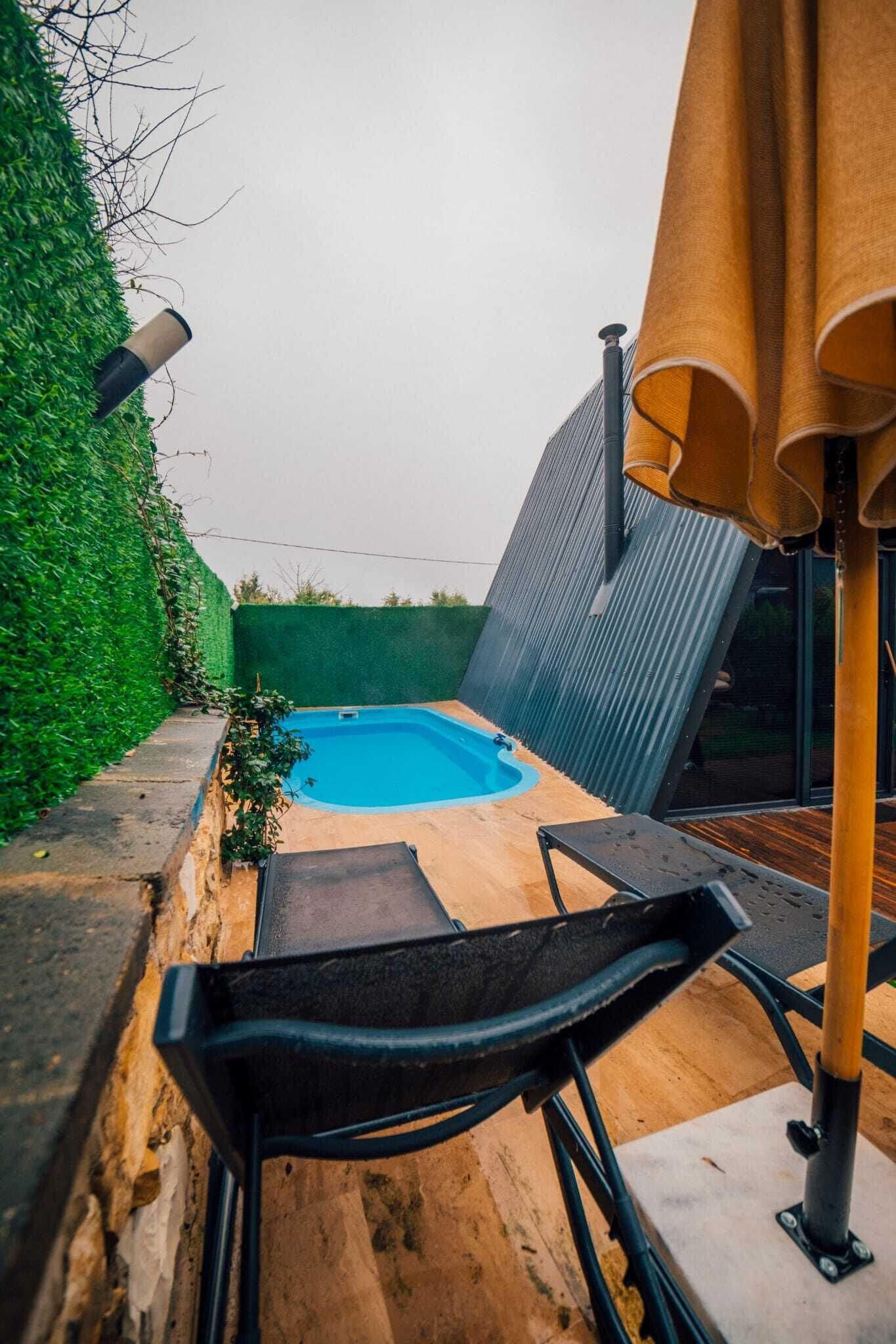 A small outdoor pool with a wooden deck and a metal chair.