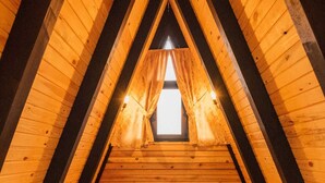 A cozy attic bedroom with wooden walls and a sloped ceiling, featuring a neatly made bed with pillows and a rolled towel. - KARMATTE BUNGALOW  (Kartepe)