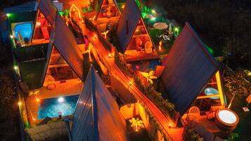 A resort with multiple triangular-roofed cabins, a swimming pool, and outdoor seating areas.
