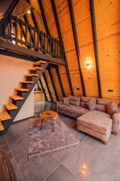 Una habitación estilo loft con escalera de madera, sofá modular y una pequeña mesa redonda.