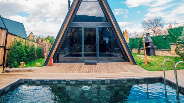 A modern house with a triangular roof, a swimming pool, and a wooden deck. - KARMATTE BUNGALOW  (Kartepe)