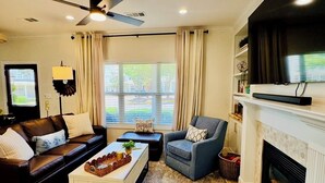 A living room with a sofa, armchair, coffee table, fireplace, and a ceiling fan. -     Freshly Remodeled Oxford Retreat 1 Mile to Ole Miss & The Square (Oxford)