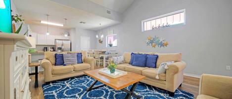 A spacious living room with a high ceiling, a dining area, and a kitchen.