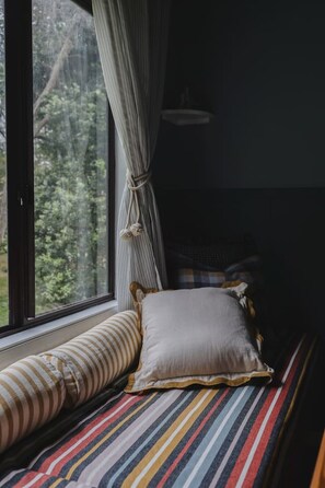 A cozy room with a bed, a window with curtains, and a view of trees outside.