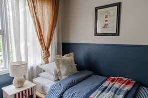 A bedroom with a bed, a nightstand, a lamp, a window with curtains, and a framed picture on the wall. - Poppy`s Place - Denmark (Denmark)