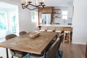 A modern kitchen with wooden cabinets, a large island, and a dining area with a wooden table and chairs. - Waterfront Retreat - Private Dock & Hot tub (Monkey Island)