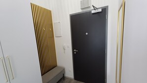 A room with a black door, a bench, a white wall-mounted phone, and a small air conditioning unit. - LUNEX Apartment (Jihočeský kraj)