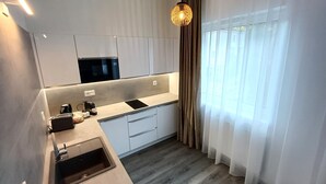 A modern kitchen with a built-in microwave, a sink, and a countertop with a coffee maker. - LUNEX Apartment (Jihočeský kraj)