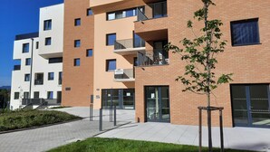 A modern multi-story building with a brick facade, balconies, and a gated entrance. - LUNEX Apartment (Jihočeský kraj)