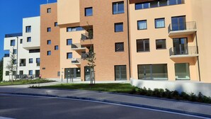 A modern apartment building with multiple balconies, a flat roof, and a paved entrance area. - LUNEX Apartment (Jihočeský kraj)