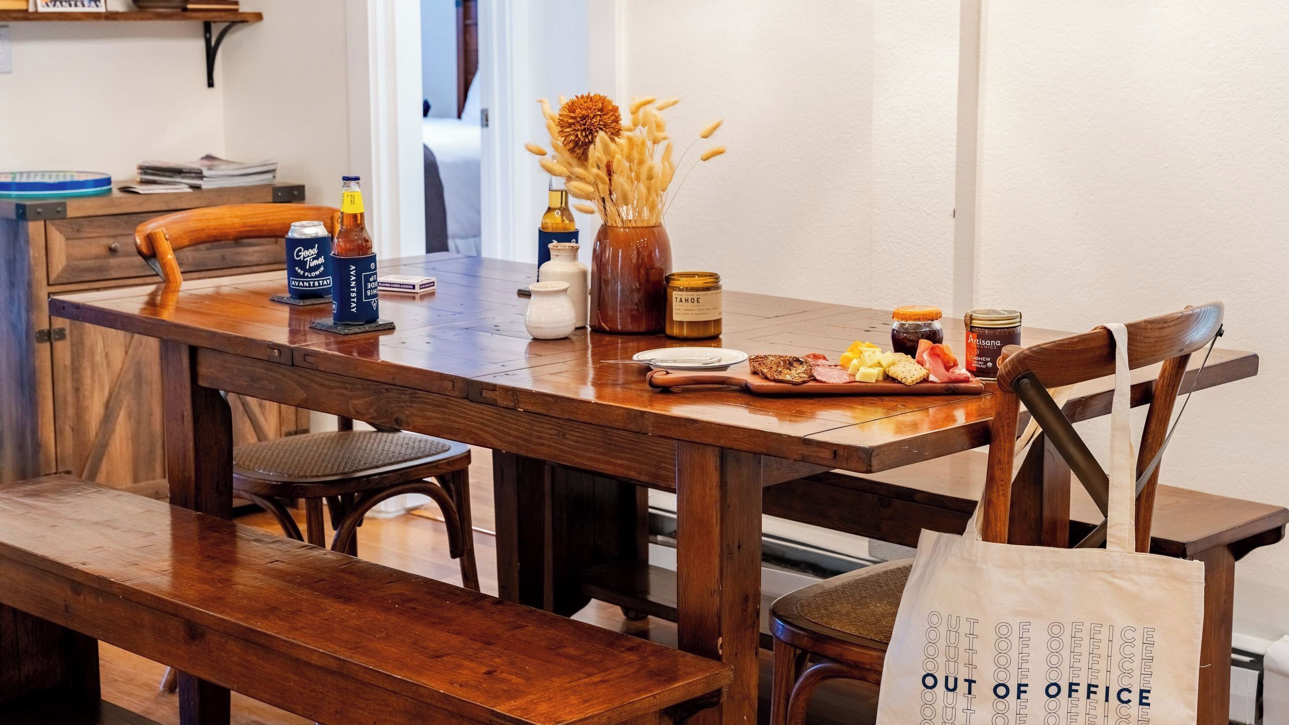 Una mesa de madera con diversos alimentos, una botella de salsa y un tarro de miel.
