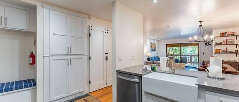 A modern kitchen with white cabinets, a dishwasher, and a large island with a sink.