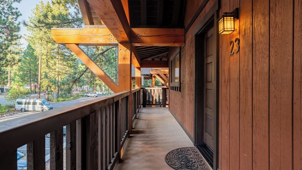 A wooden balcony with a view of a road and parked vehicles, a door with the number 23, and a small rug at the entrance. - Walk to Lake, Dining+shops 5mins to Ski Resort Incline Paradise by Avantstay (Incline Village)