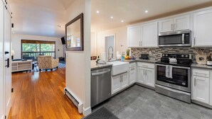 A modern kitchen with white cabinets, stainless steel appliances, and a large window overlooking a deck. - Walk to Lake, Dining+shops 5mins to Ski Resort Incline Paradise by Avantstay (Incline Village)