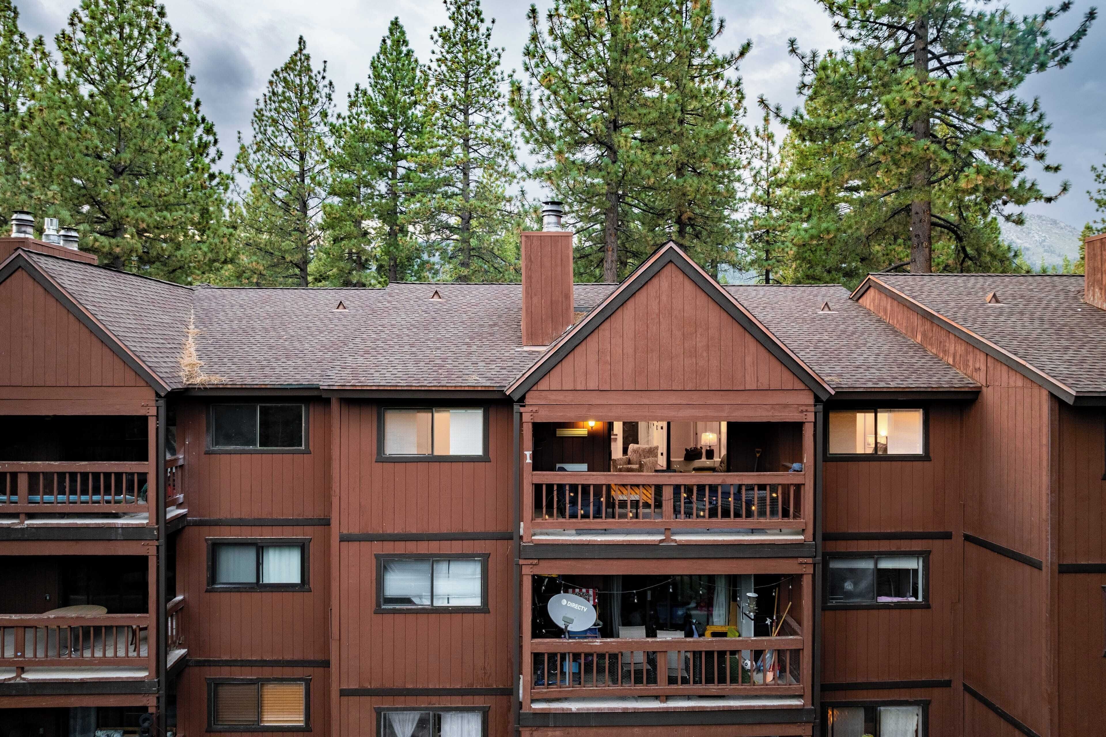 A multi-story wooden building with balconies and windows, surrounded by trees.