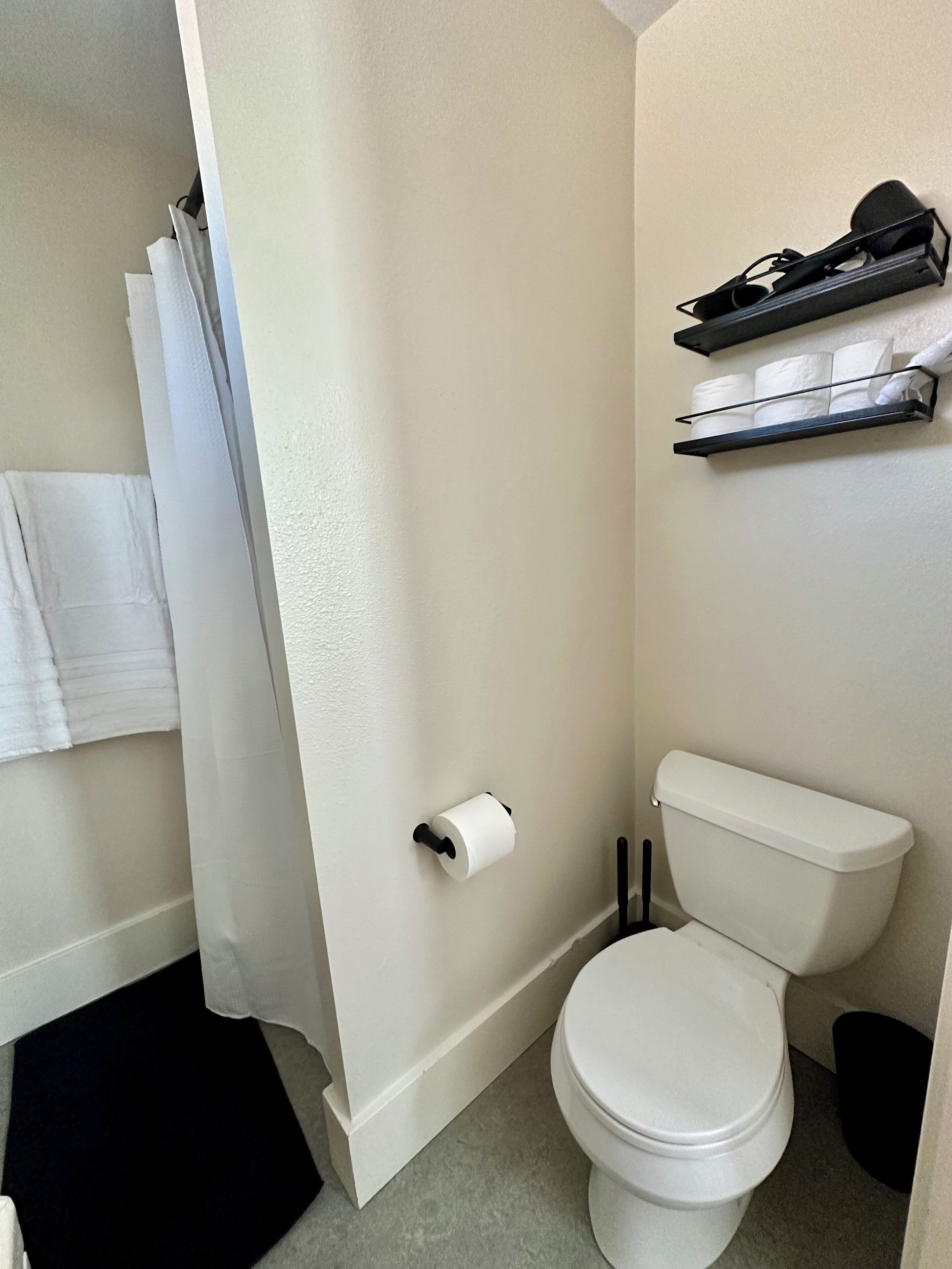 Un bagno piccolo con il water, un porta asciugamani e uno scaffale con articoli da toilette.