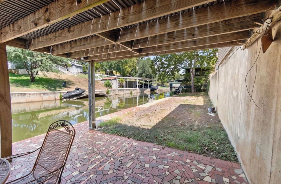A covered patio area with a mosaic-tiled floor and a metal chair.