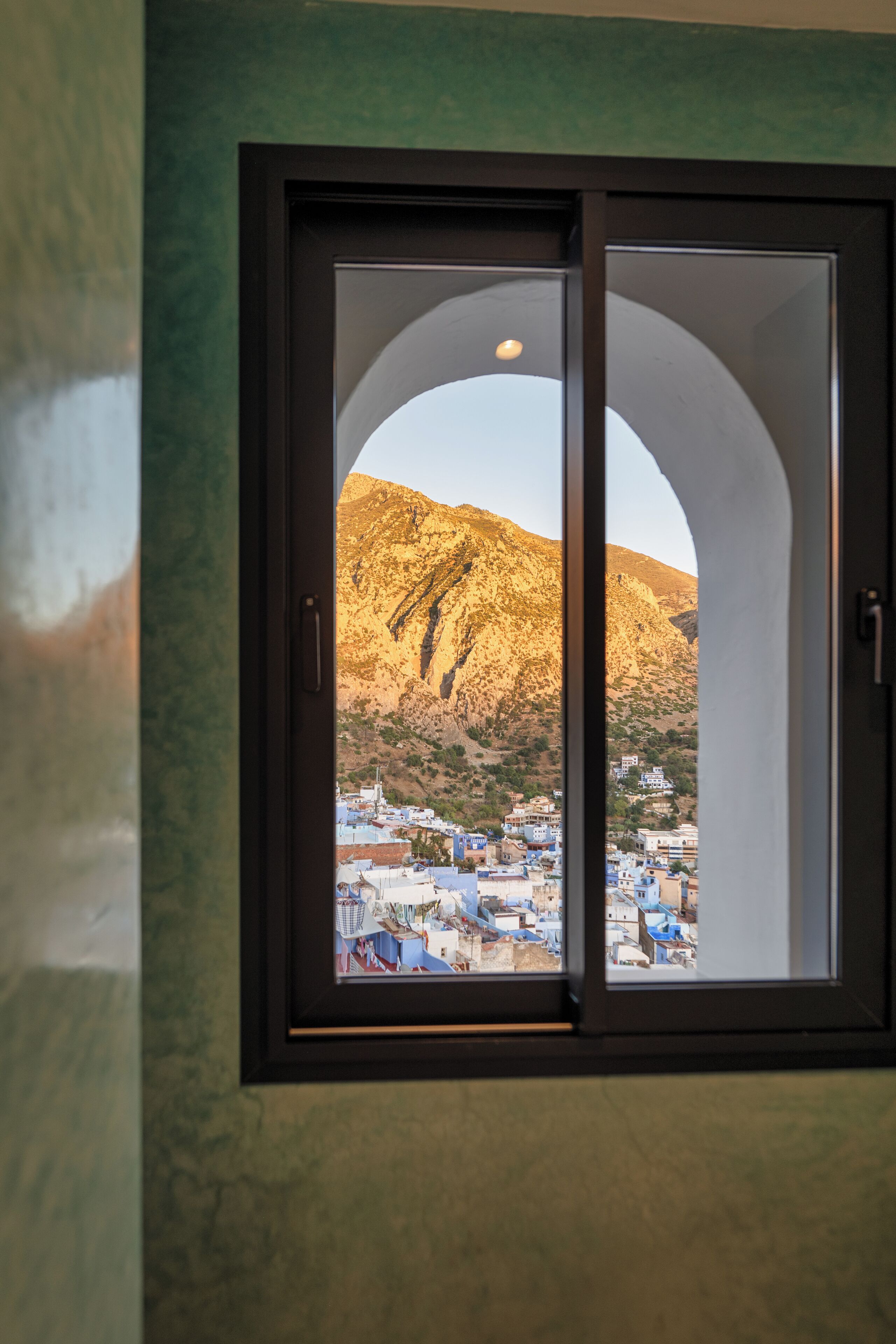A window with a view of a mountainous landscape and a town below.