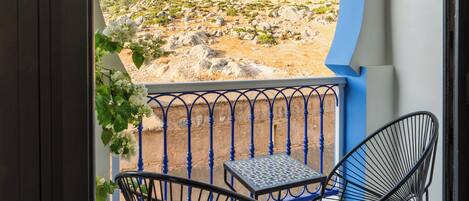 Un balcon avec deux chaises et une table, donnant sur un paysage montagneux.