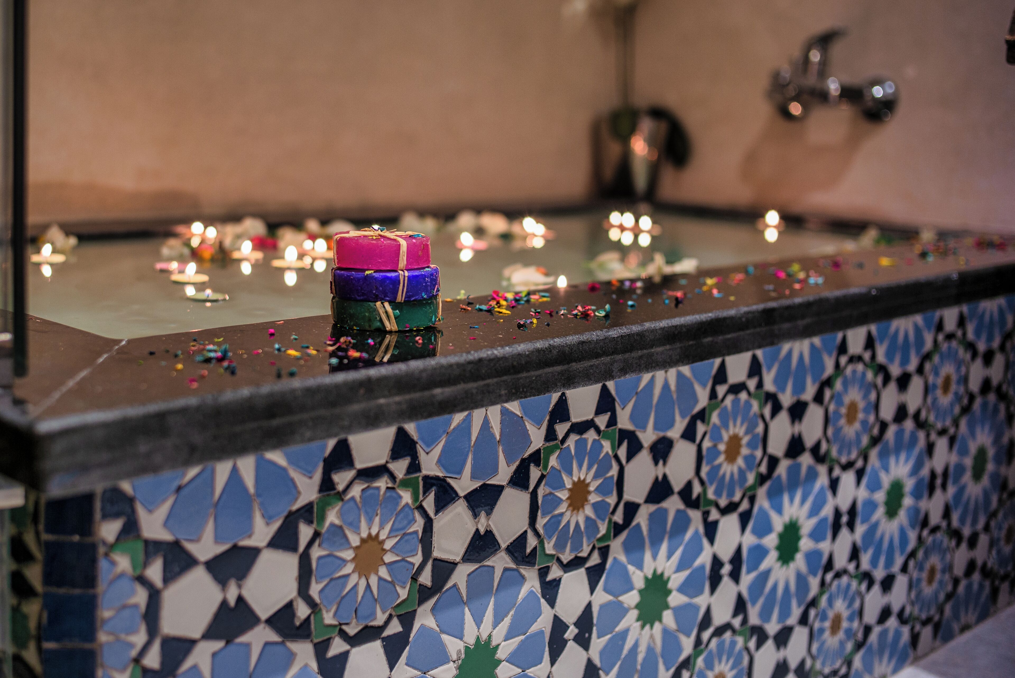 A tiled wall with a floral pattern, a small stack of colorful candles, and scattered confetti.