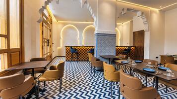 A modern dining area with a checkered floor, wooden furniture, and a central column with a patterned design.