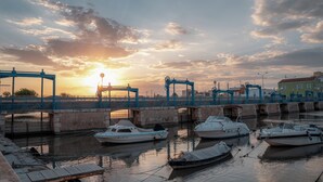 Una marina con barche ormeggiate, un ponte e un tramonto sullo sfondo.
