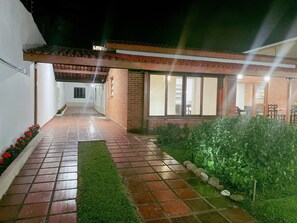 A covered outdoor area with a tiled floor, a brick wall, and a window overlooking the interior. - Beach House Unid. 2 Casas Praia Guarujá (Guarujá)