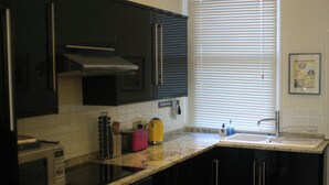 A kitchen with dark cabinets, a microwave, a toaster, and a sink. - Breathtaking Flat in Central Bath !! (Bath)