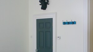 A room with a dark green door, a coat rack with hooks, a small table with a brown top, and a blue storage box. - Breathtaking Flat in Central Bath !! (Bath)